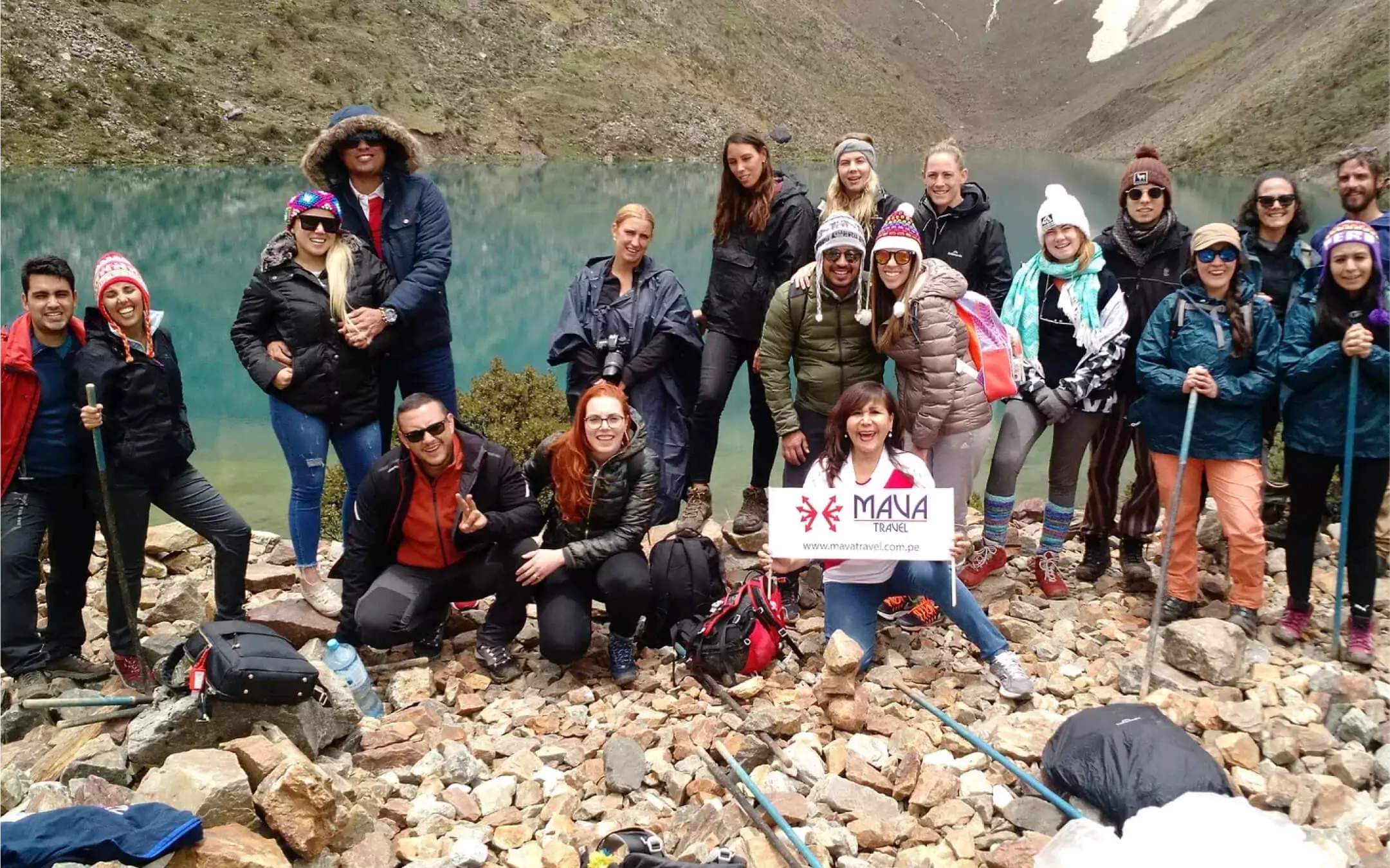 Tour group posing at Humantay Lake with Mava Travel Perú sign