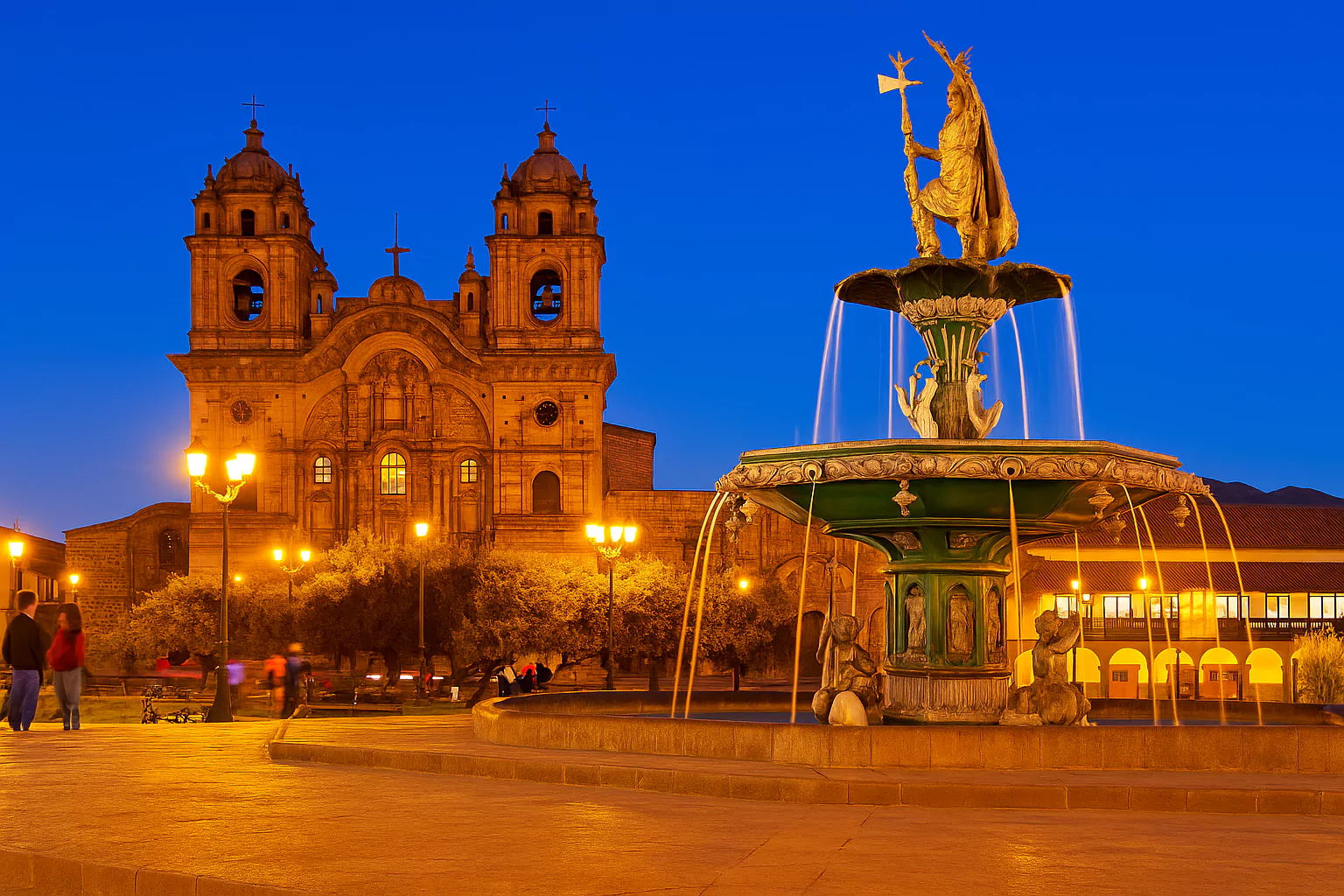 Illuminated Cusco Cathedral and fountain in Plaza de Armas at dusk