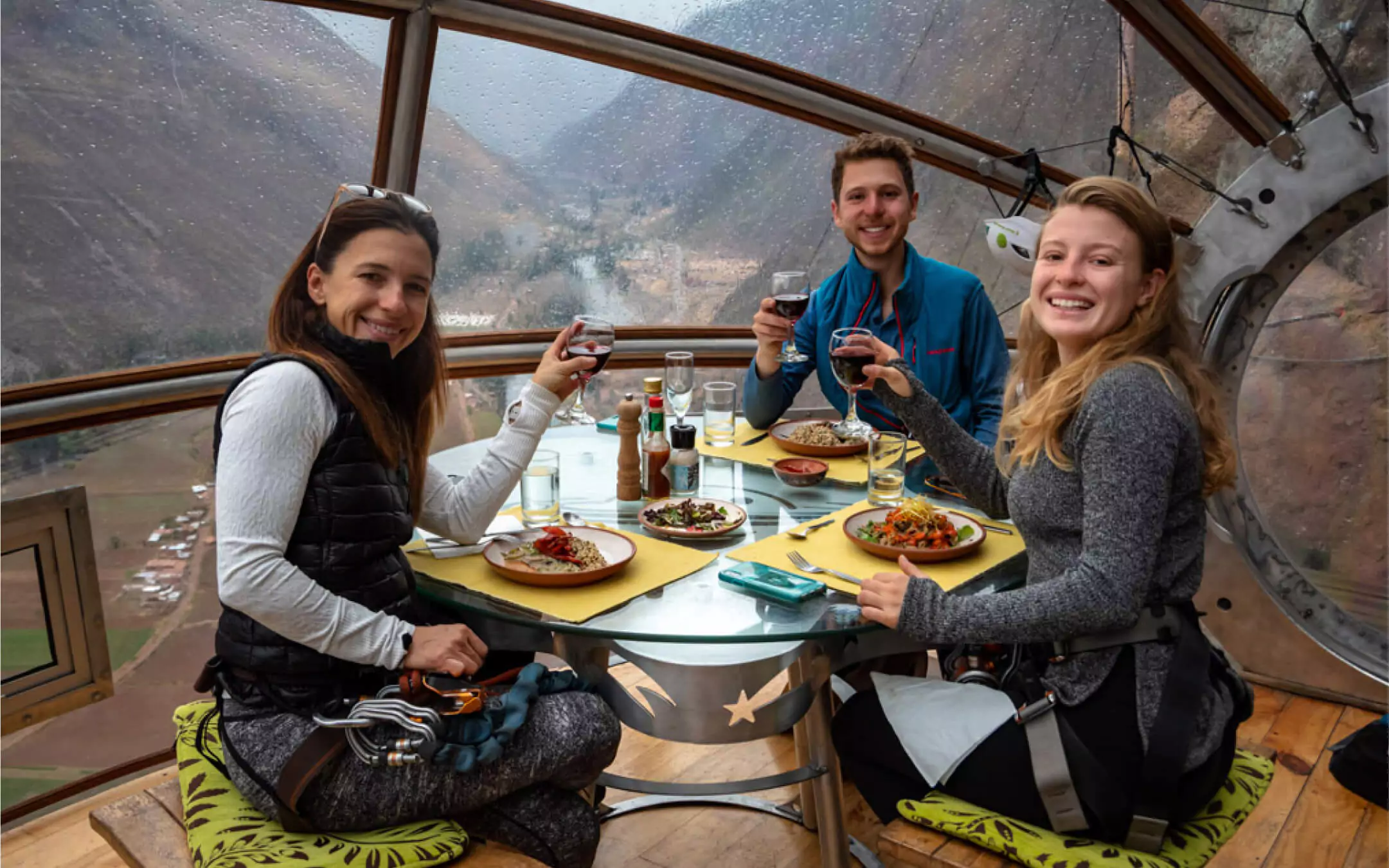 Tourists dining inside a glass pod suspended on a cliff in the Sacred Valley